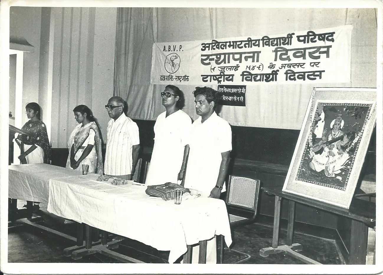 The dais at the ABVP Sthapna Diwas observance with Suryakant Bali and Mahesh Chand Sharma, under the Foundation Day banner with a portrait of Saraswati